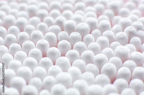 Closeup view from above on round pack of cotton buds on pink background