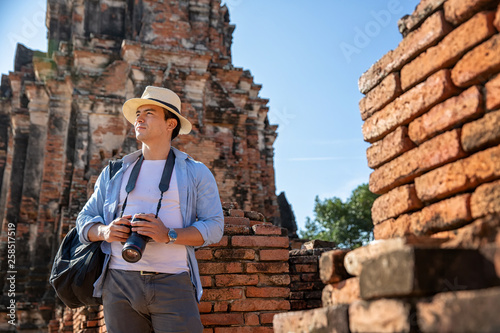 Eastern Asia summer holidays. Caucasian man tourist from back looking at Wat Chaiwatthanaram temple. Travelers take pictures with DSLR cameras. Travel in old city of Ayutthaya, Thailand. Asia tourist.