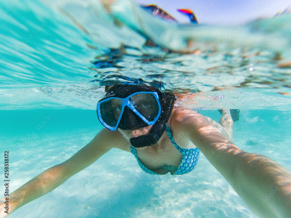 Fototapeta premium woman taking an underwater selfie while snorkeling in crystal clear tropical water