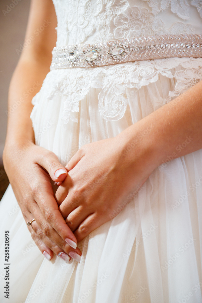 Bride's hands folded on a white wedding dress Bride's hands folded on a white wedding dress