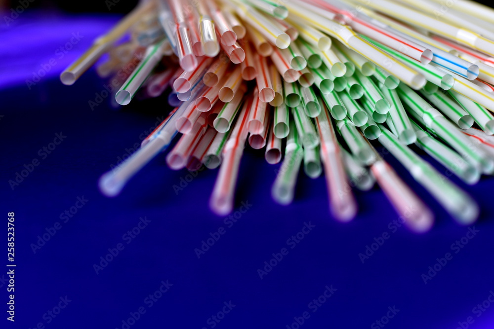 Bunch of single use disposable colorful plastic straws on the blue ...