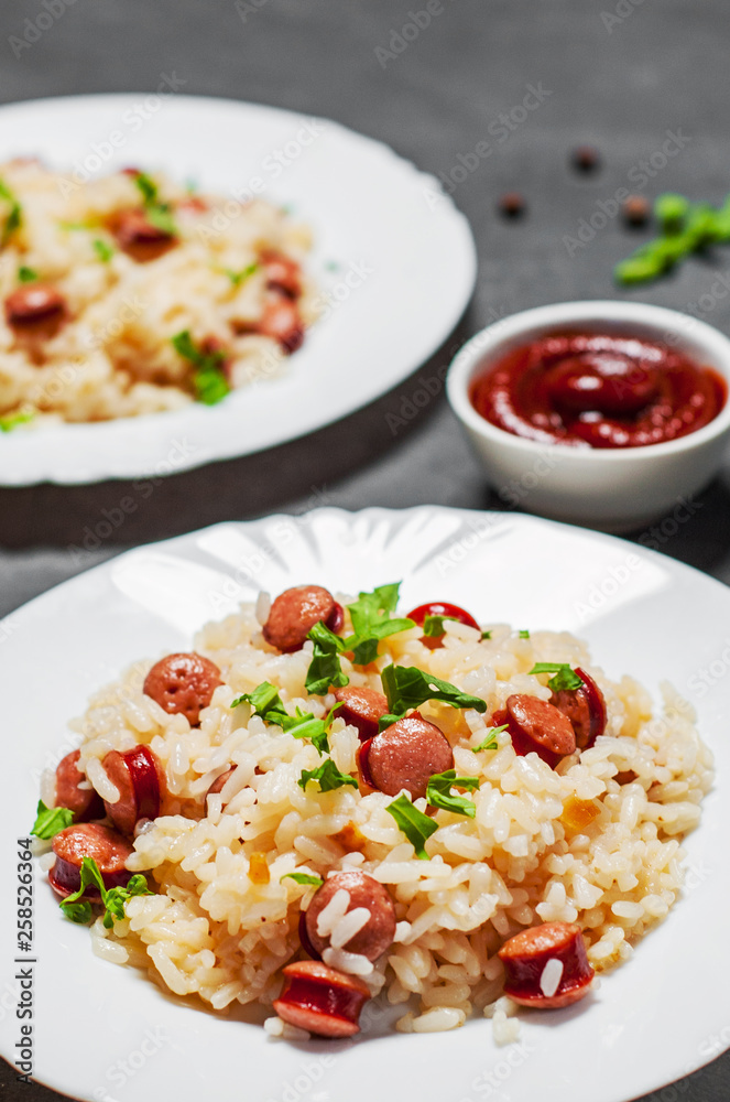 rice with smoked sausage in white plate on Dark grey black slate background rice with smoked sausage in white plate on Dark grey black slate background