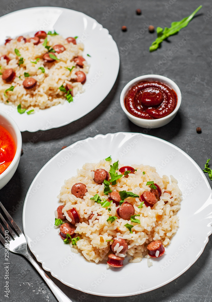 rice with smoked sausage in white plate on Dark grey black slate background rice with smoked sausage in white plate on Dark grey black slate background