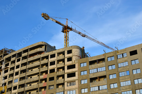 Large construction site with cranes on the blue sky background. Construction worker truss installation - Image © MaxSafaniuk