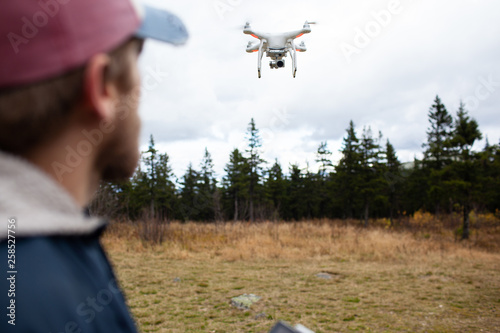 Male tourist exploring new places. Handsome bearded man on nature with fuel. Using drone photographs and shoots nature