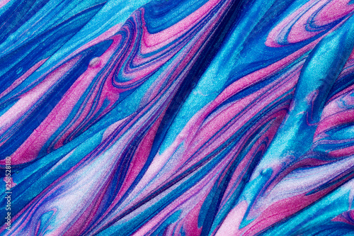 Abstract textured background of pink and blue metallic glitter paint swirls