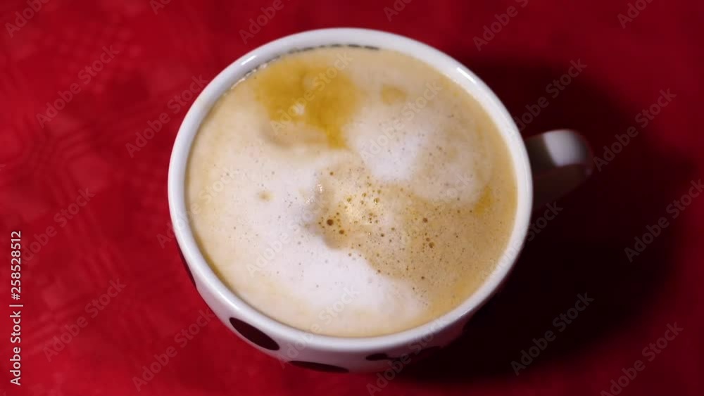Sweet sugar cube being dropped in a cappuccino beverage mug, close up shot Sweet sugar cube being dropped in a cappuccino beverage mug, close up shot