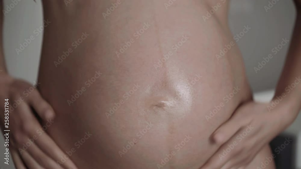 Bare pregnant moistens tummy with lotion Bare pregnant moistens tummy with lotion