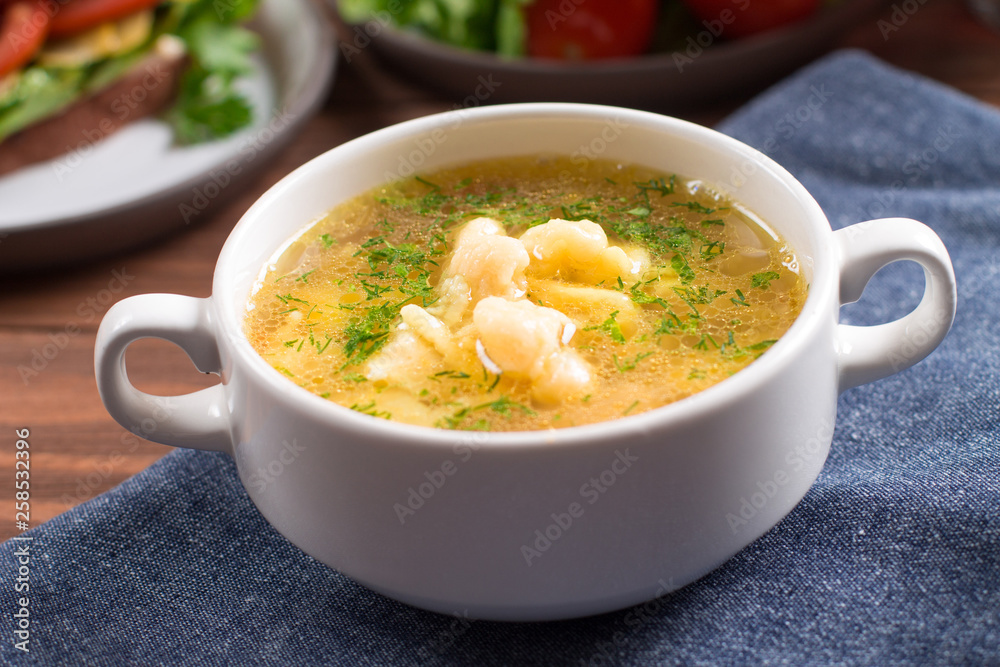 Chicken soup, potato gnocchi, with fresh herbs. Wooden background Chicken soup, potato gnocchi, with fresh herbs. Wooden background