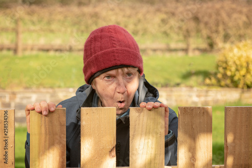 Shocked mature woman looking over fence 