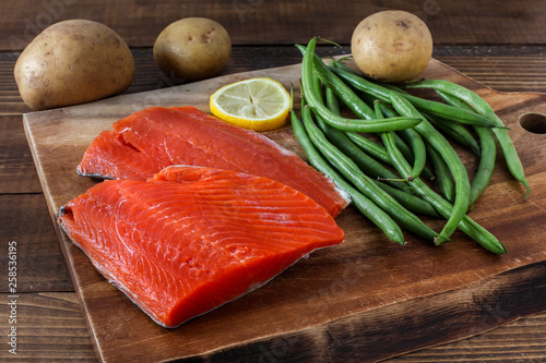 Sock eyed salmon with organic green beans, potatoes and lemon on wooden cutting board photo