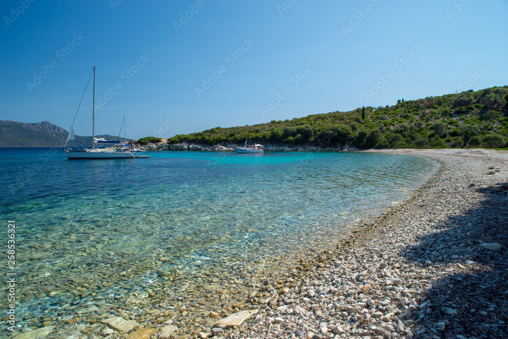 Beach and rocky coastline landscape with yacht