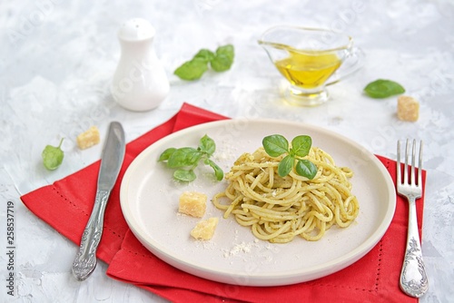 Spaghetti with pesto sauce and parmesan cheese on a white ceramic plate. Italian food.