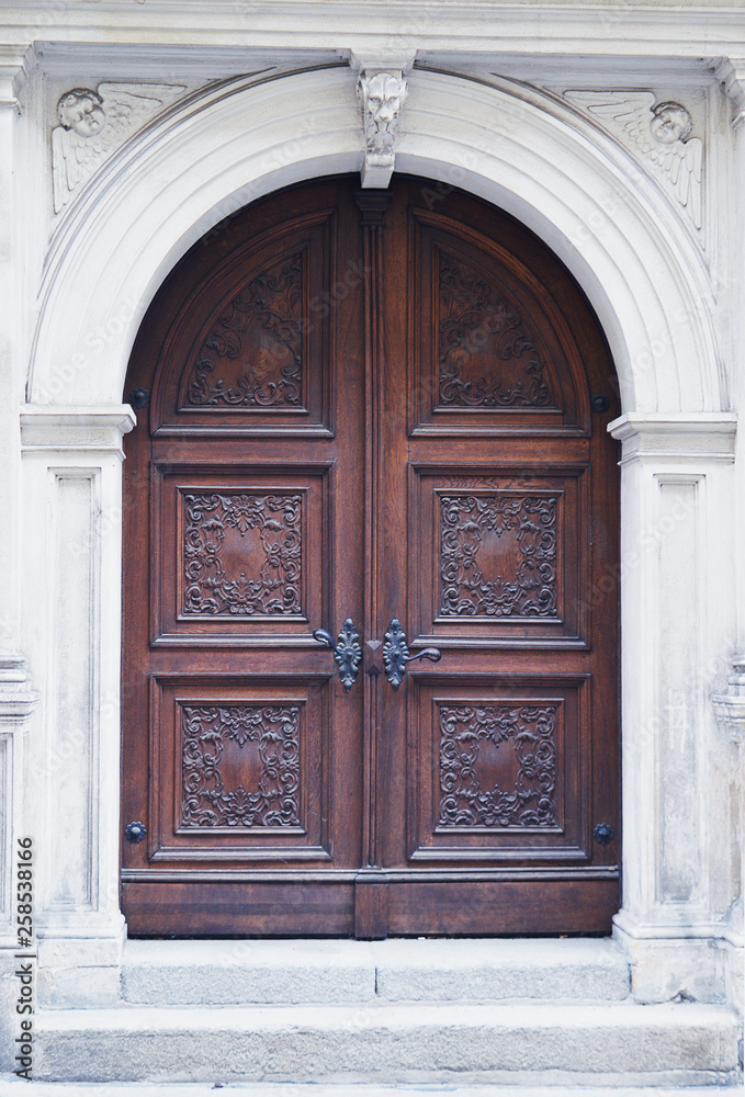 Arched wooden door with white stone surrond