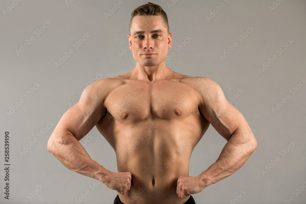 Fototapeta premium handsome male athlete with pumped muscles on gray background