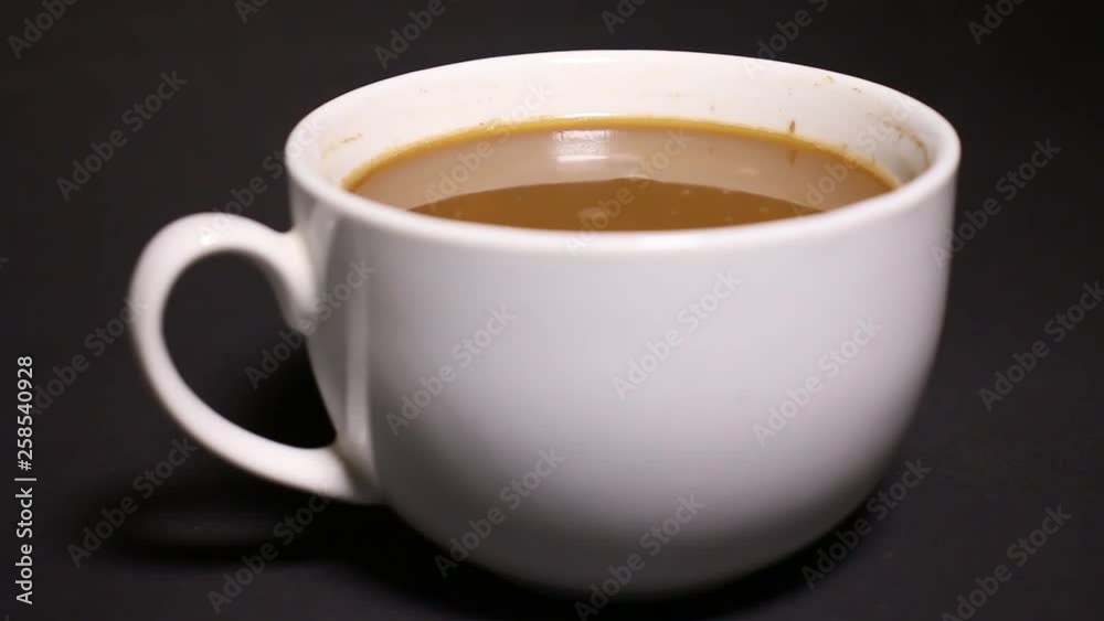 Mixed bleached coffee in a white cup on a black background. Mixed bleached coffee in a white cup on a black background.