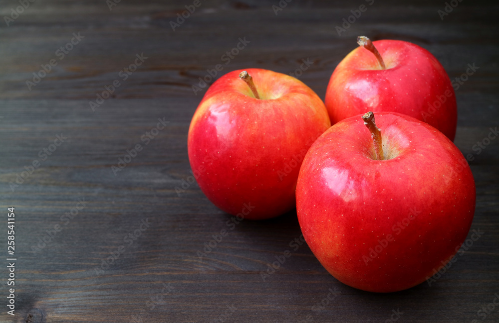 Three red apples on dark colored wooden table with free space for text and design Three red apples on dark colored wooden table with free space for text and design