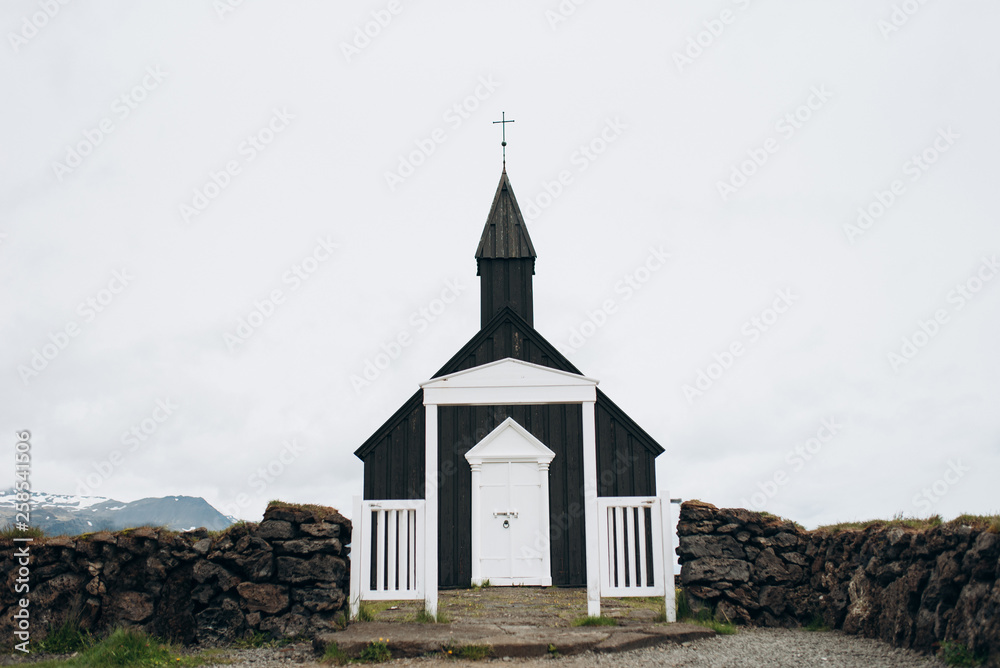 Black wooden church in Iceland against the background of the mountains. Budir Church.