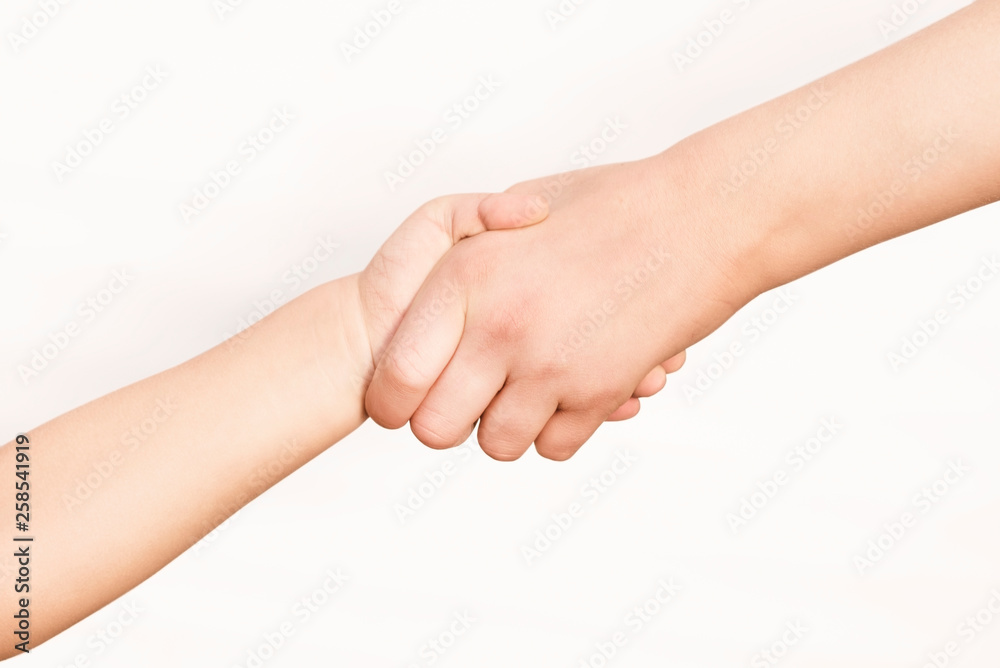 The hand of a young girl helps the hand of a little boy, hold her and pulls up. Concept of help The hand of a young girl helps the hand of a little boy, hold her and pulls up. Concept of help