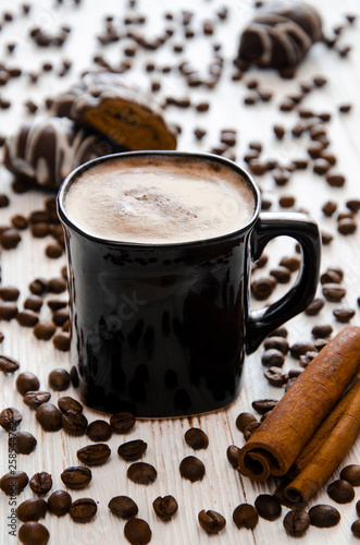 Fototapeta Naklejka Na Ścianę i Meble -  A cup of coffee with cinnamon and whipped cream. Coffee grains and chocolate gingerbread.