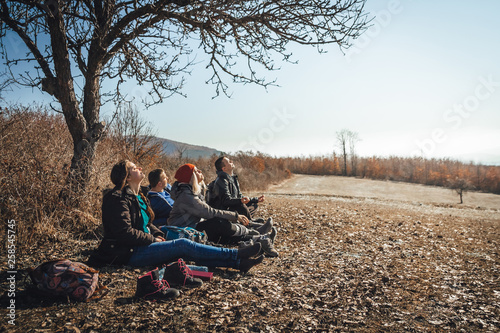 Four friends chilling under the tree and enjoying the sun. Happy moments with autumn colors and sunny day