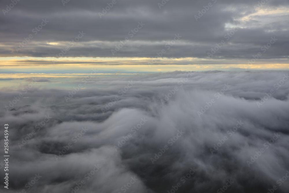 Abstract photograph above the clouds, sea of clouds effect, flying through the sky, aerial view, white puffy clouds and blue sky. Low pressure front atmospheric effect, cloudscape, cloudy weather