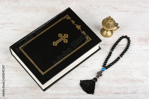 Holy Bible, rosary beads with cross and incense burner on white wooden background. Religion concept and faith