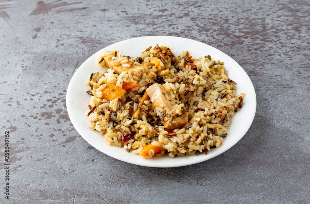 Chicken with pecans and wild rice on a plate on a gray background Chicken with pecans and wild rice on a plate on a gray background