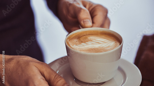 Mann hält eine Tasse Cappuccino in der Hand