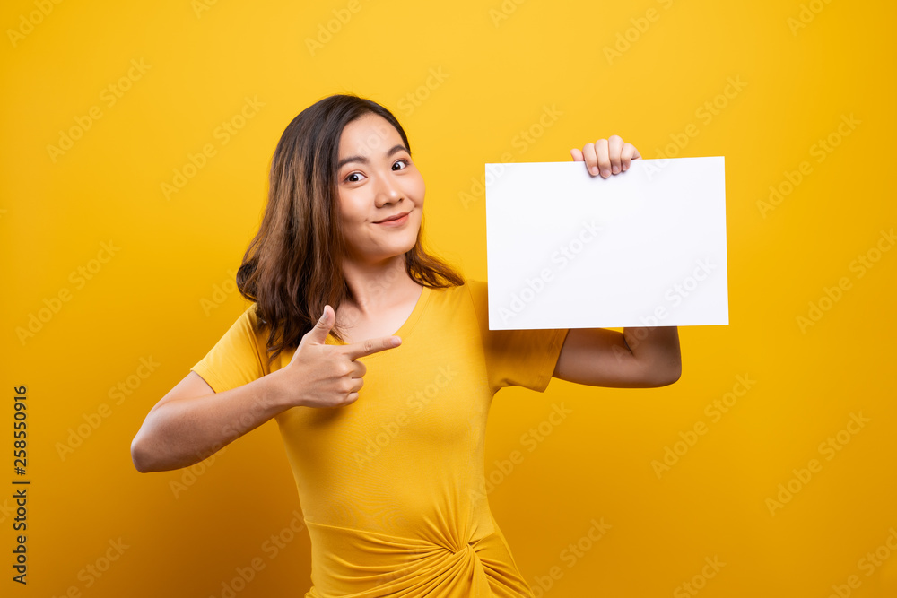 Woman showing paper copy space isolated over yellow background Woman showing paper copy space isolated over yellow background