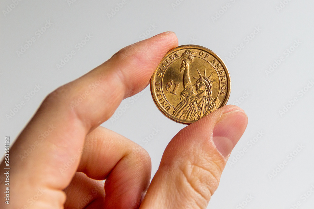 United States one dollar coin with Liberty Statue being held by fingers United States one dollar coin with Liberty Statue being held by fingers