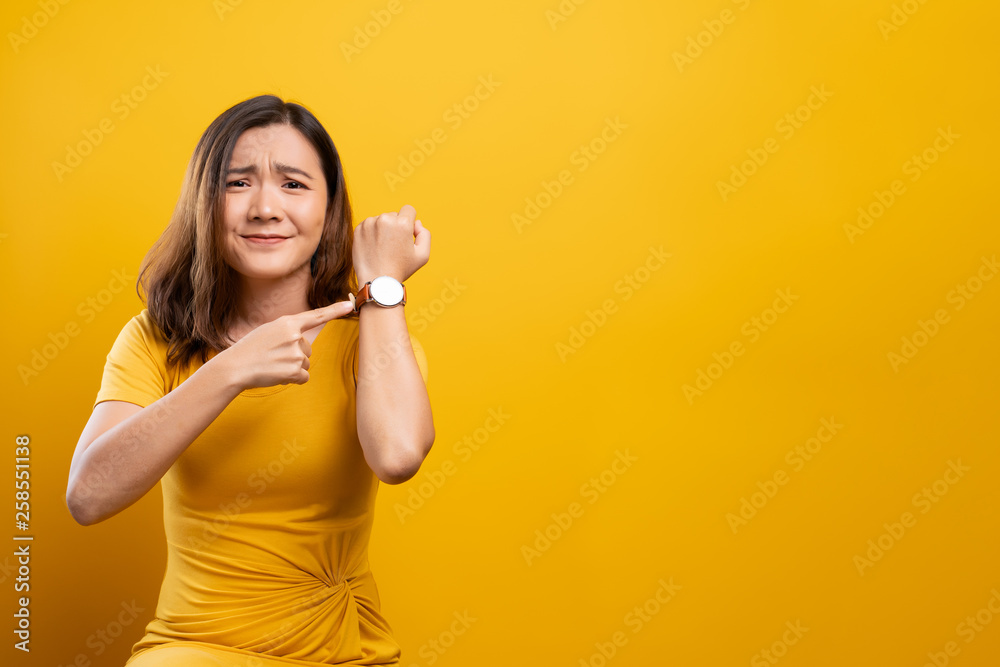 Shocked woman holding hand with wrist watch isolated on a yellow background Shocked woman holding hand with wrist watch isolated on a yellow background