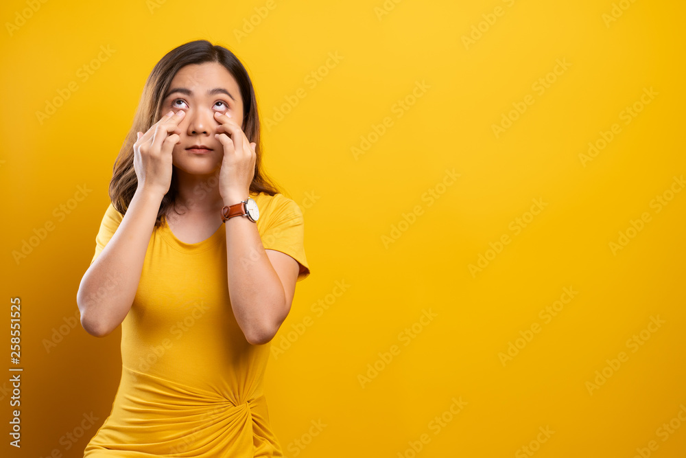 Woman has eyes pain isolated over yellow background Woman has eyes pain isolated over yellow background