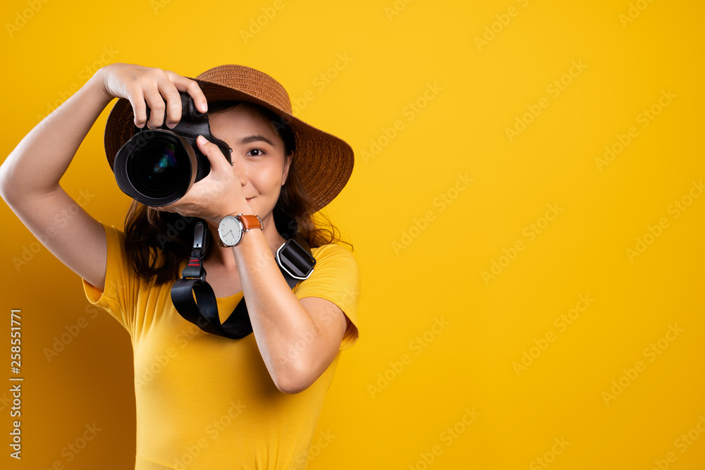 Woman in summer hat standing with photo camera isolated over yellow background Woman in summer hat standing with photo camera isolated over yellow background