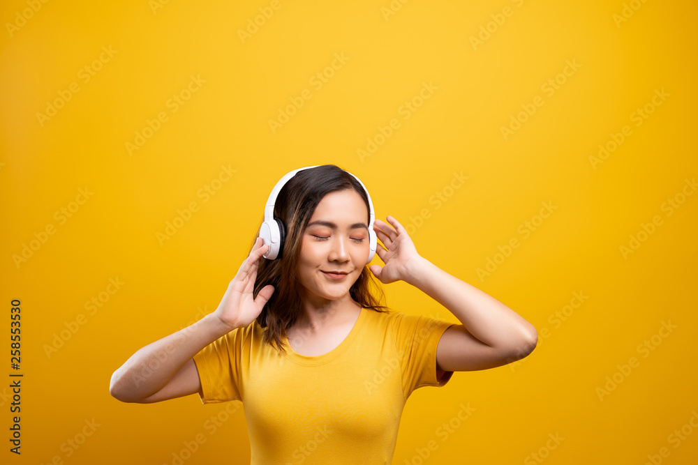 Fototapeta premium Woman with headphones listening music on isolated yellow background