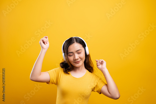 Woman with headphones listening music on isolated yellow background