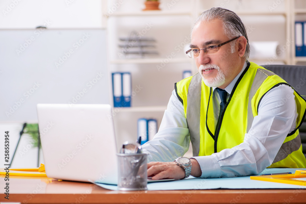 Aged construction engineer working in the office Aged construction engineer working in the office