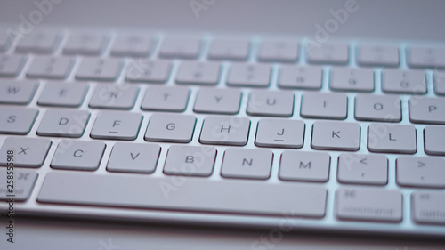 A close-up of a white computer keyboard on a white desk.