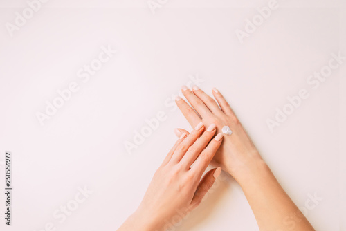 Woman’s hands applying moisturizing cream, copy-space.