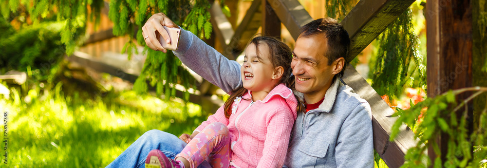 Fototapeta premium Dad and daughter doing selfie in park