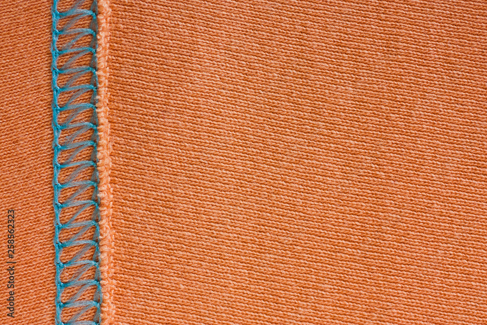 Fototapeta premium Empty orange knitted fabric with decorative elements. Knit texture with stitching. Coral background for wallpaper and other elements of your design.