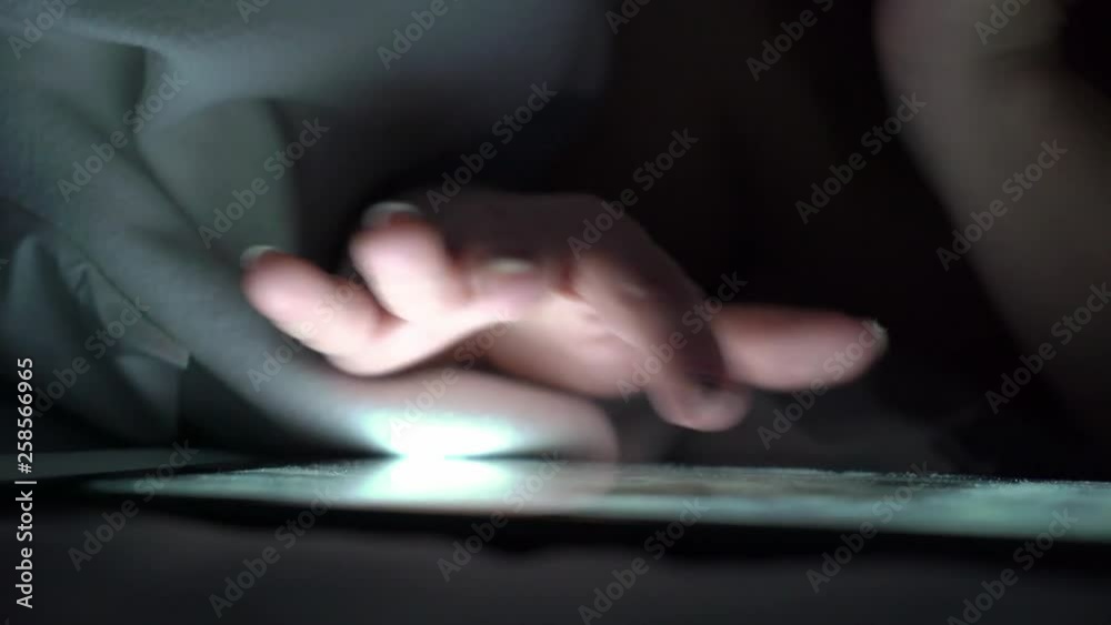 Young woman using tablet on the bed before she sleeping at night. Mobile addict or insomnia concept. Young woman using tablet on the bed before she sleeping at night. Mobile addict or insomnia concept.
