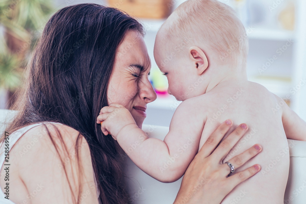 concept of motherhood:happy mother playing with one year old baby in the room for children concept of motherhood:happy mother playing with one year old baby in the room for children