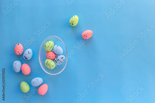 Colorful eggs in large glass egg. Happy Easter concept. Top view, flat lay.