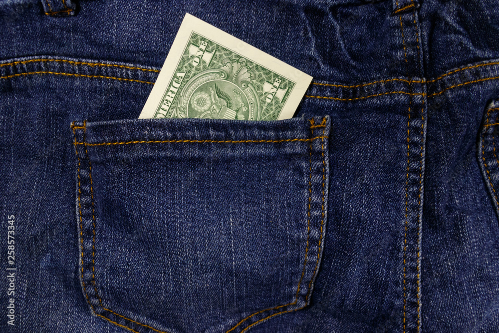 One dollar bill in a pocket of blue jeans One dollar bill in a pocket of blue jeans