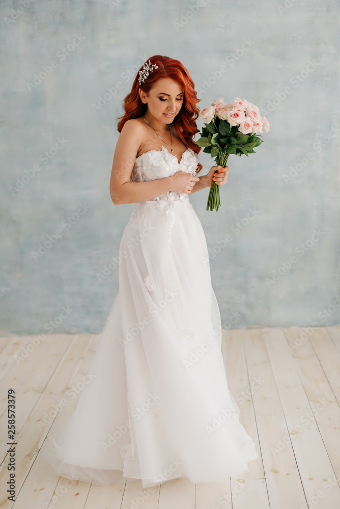 Happy red-haired bride stands with bouquet in her hands Happy red-haired bride stands with bouquet in her hands