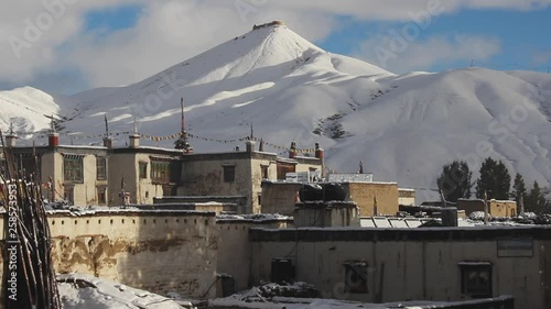 Beautiful view of snow capped mountain peak with town buildings in foreground at Nepal Mustang Chhosar photo