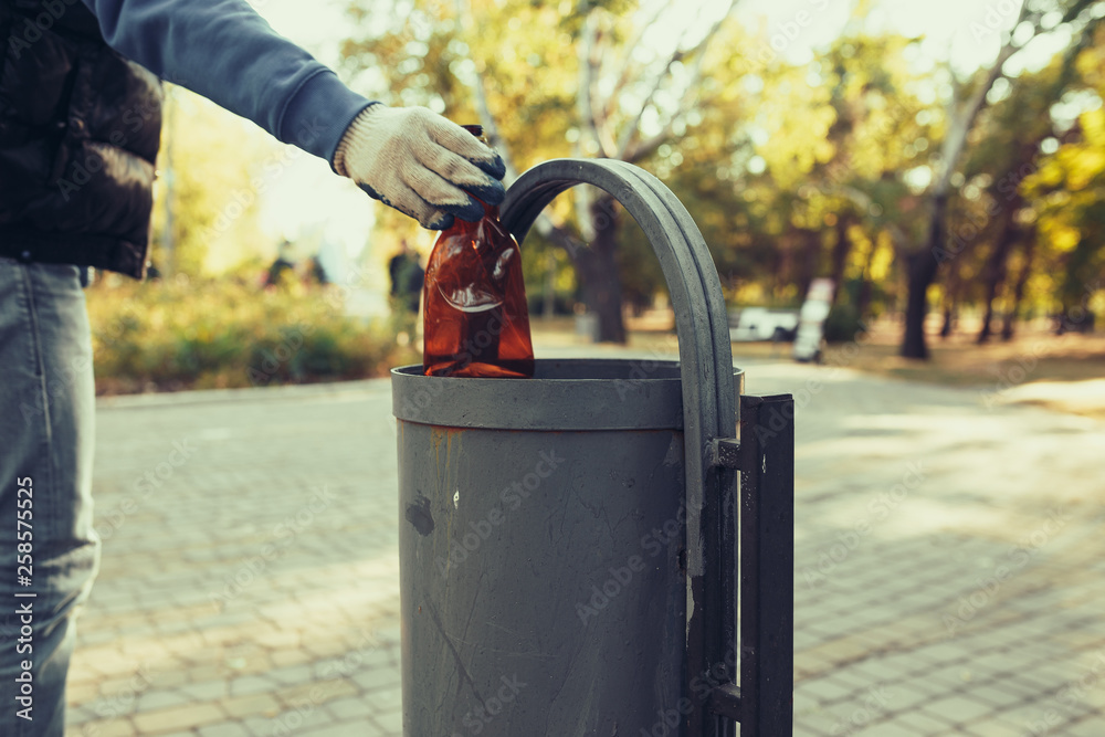 young man picking up trash outdoor. close up young man picking up trash outdoor. close up