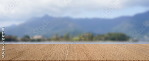 abstract blur viewpoint of natural park ,forest,lake and mountain with brown wood perspective table for show,promote,ads product or content on display concept