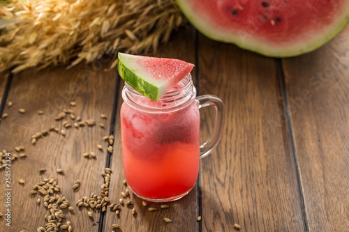 Fresh watermelon smoothie in the mason jar and wheat spike on wooden table